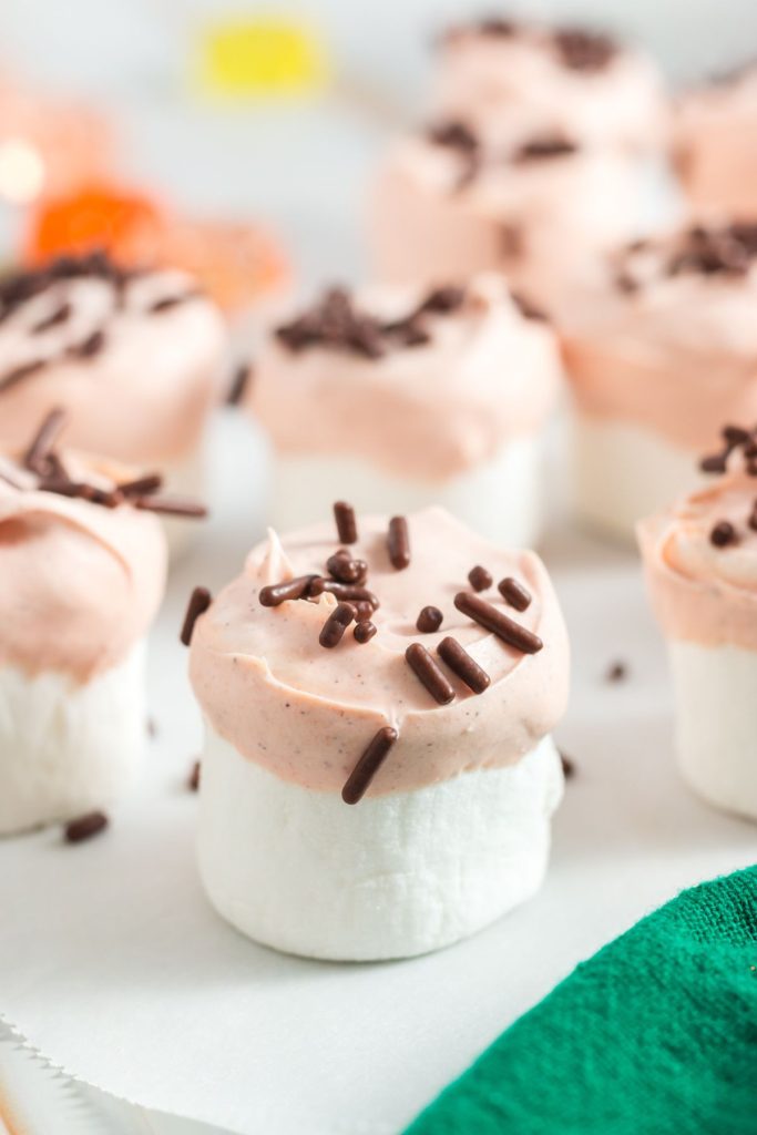 marshmallows that are half covered in orange frosting with brown sprinkles