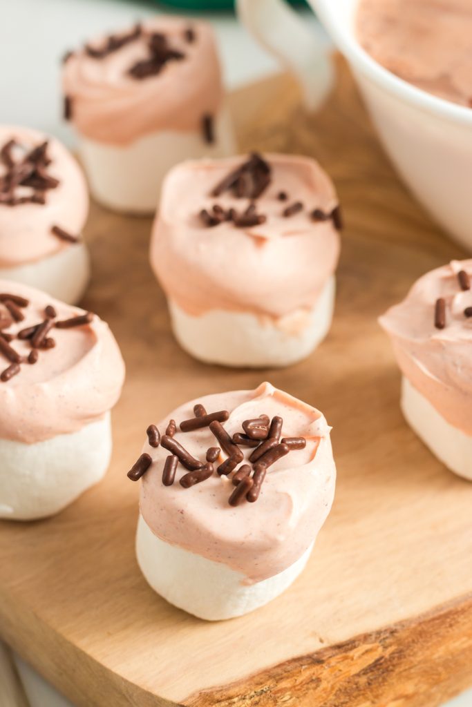 large marshmallows dipped half way in a light orange candy and brown sprinkles on the top