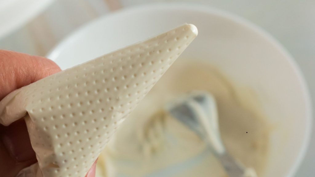 the corner of a plastic piping bag filled with melted white chocolate